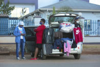 People sell clothes displayed on their car by the side of a busy road in Harare, Zimbabwe, Tuesday, June, 23, 2020. Cars have become mobile markets in Zimbabwe where enterprising residents are selling goods from their vehicles to cope with economic hardships caused by the coronavirus. With their car doors and trunks wide open by the side of busy roads, eager sellers display a colorful array of goods in Harare, the capital. (AP Photo/Tsvangirayi Mukwazhi)