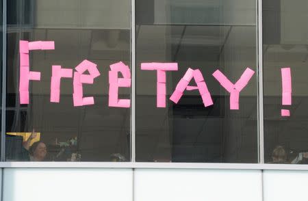 An office worker gives a thumbs up after placing a sign in the windows of her building across the street from Denver Federal Court where the Taylor Swift groping trial jury selection resumes in Denver, U.S., August 8, 2017. REUTERS/Rick Wilking