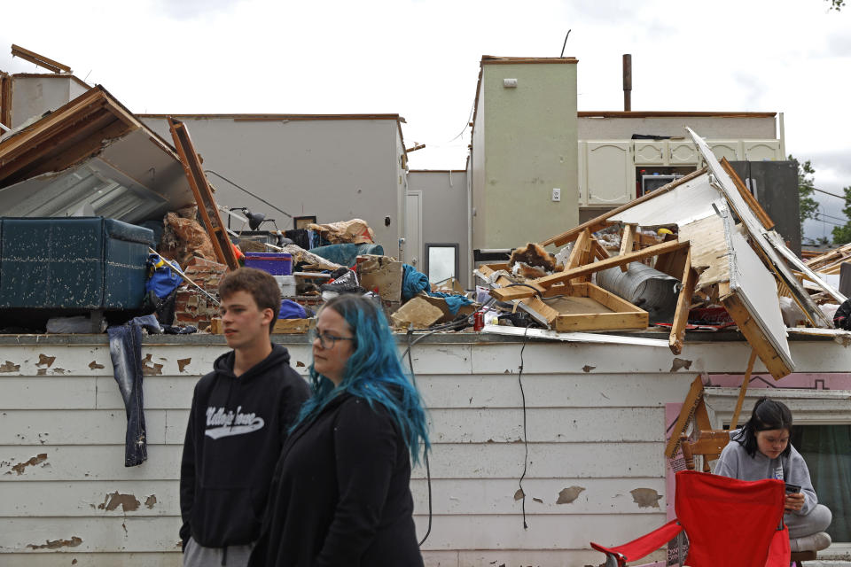 Woodridge, Ill., homeowners Bridget Casey and his son Nathan Casey, 16 stands in front of their damaged home after a tornado passed through the area on Monday, June 21, 2021. (AP Photo/Shafkat Anowar)