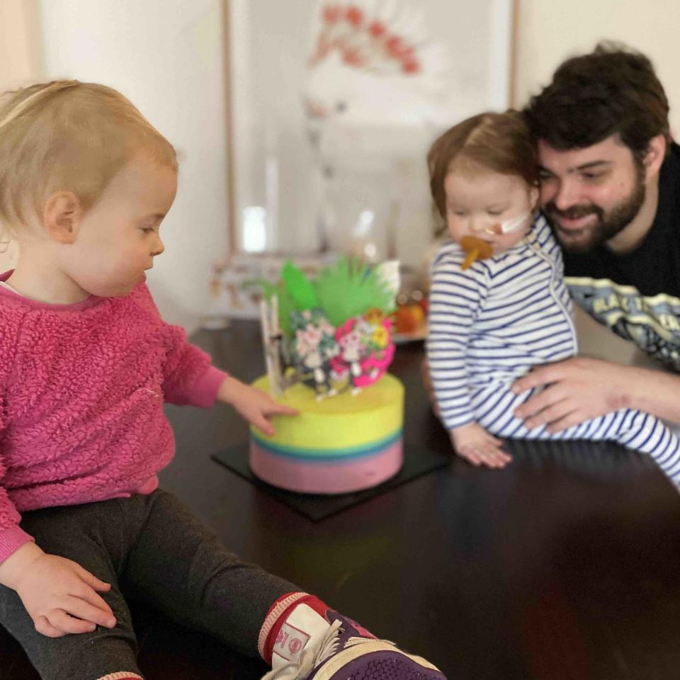 Adrien holds Chloé as she and Nina look at their birthday cake. 