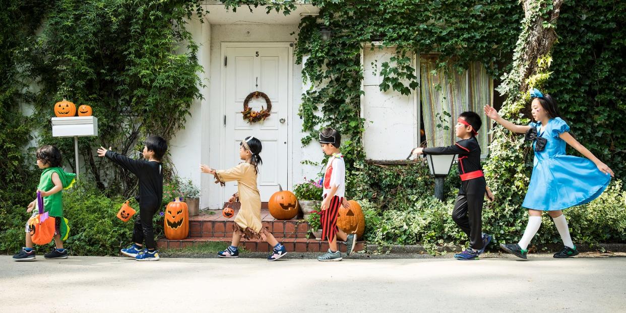 kids walking past an ivy covered house in halloween costumes