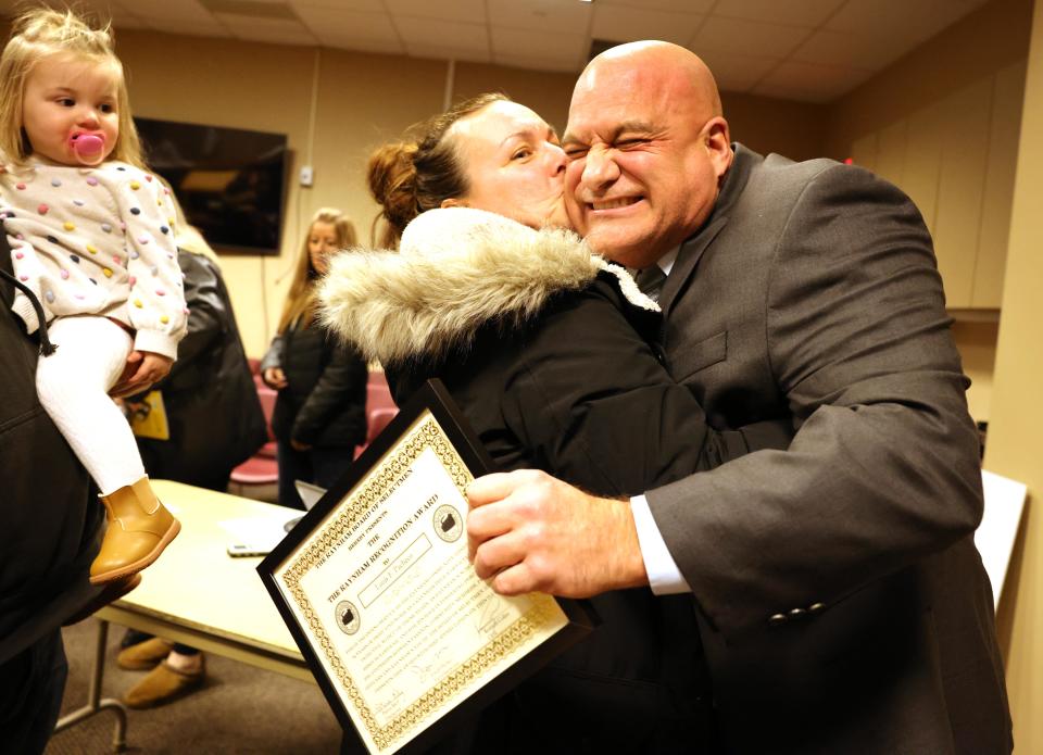 Raynham Police Det. Louis F. Pacheco, right, is congratulated by Traci Arruda at Town Hall on Tuesday, Jan. 23, 2024. Selectmen presented the Raynham Recognition Award to Pacheco, who is the Raynham school resource officer and B-R head football coach.