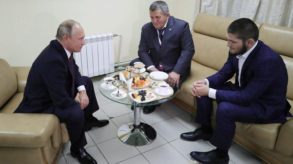 Russian President Vladimir Putin (L) speaks with UFC lightweight champion Khabib Nurmagomedov (R) and his father. (Photo by Mikhail KLIMENTYEV / SPUTNIK / AFP)