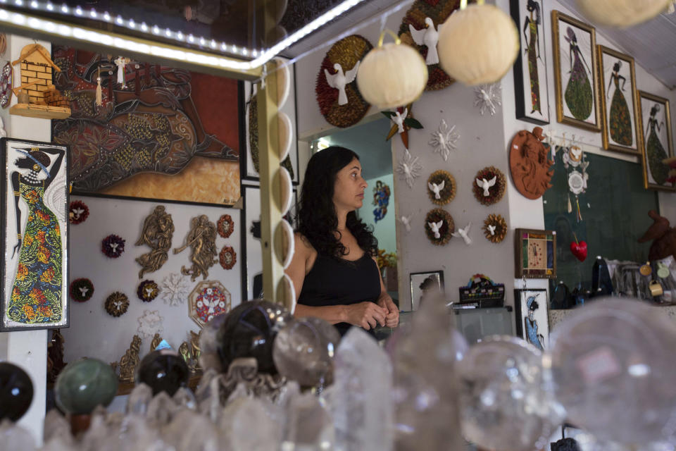 In this Jan. 3, 2019 photo, shop owner Vania Caldeira worries about the future of her business, after the arrest of local spiritual healer Joao Teixeira de Faria, in Abadiania, Brazil. Many depend on the business brought in by de Faria. By some estimates, his "casa spiritual," or "spiritual house," drew 10,000 patients a week to the small Brazilian town. (AP Photo/Eraldo Peres)