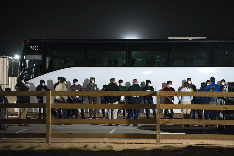 FILE - In this Sunday, March 14, 2021, file photo, migrant children and teenagers are processed after entering the site of a temporary holding facility south of Midland, Texas. The Biden administration is not requiring FBI fingerprint background checks of caregivers at its rapidly expanding network of emergency sites to hold thousands of immigrant teenagers. That alarms child welfare experts who say the waiver compromises safety. (Eli Hartman/Odessa American via AP, File)