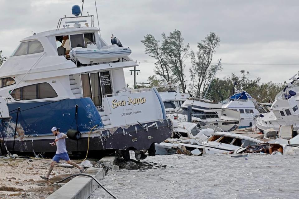 Joe Dalton, on vacation from Cleveland, Ohio, checks out beached boats at Fort Myers Wharf along the Caloosahatchee River Thursday, Sept. 29, 2022, in Fort Myers, Fla., following Hurricane Ian.