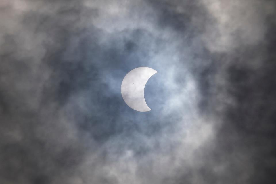 A partial solar eclipse is seen through the cloud over Jakarta, Indonesia, Thursday, April 20, 2023. A rare solar eclipse crossed over remote parts of Australia, Indonesia and East Timor on Thursday.