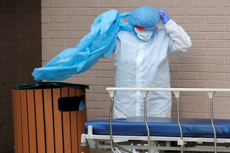 Un trabajador de la salud retira y desecha el equipo de protección personal en la basura después de sacar los cuerpos de las personas fallecidas fuera del Centro Médico Wyckoff Heights en Nueva York, Nueva York, EEUU, 2 de abril de 2020