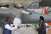 Indian Defense Minister Rajnath Singh writes onto a Rafale jet fighter as a ritual gesture during an handover cermony at the Dassault Aviation plant in Merignac, near Bordeaux, southwestern France, Tuesday, Oct. 8, 2019. France has delivered to India its first Rafale fighter jet from a series of 36 aircraft purchased in a multi-billion dollar deal in 2016. (AP Photo/Bob Edme)