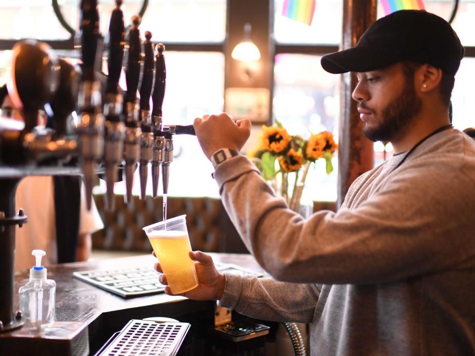 A bartender pours pints for takeaway customers at The Ten Bells pub in east London on June 27, 2020: Daniel Leal-Olivas/AFP via Getty Images