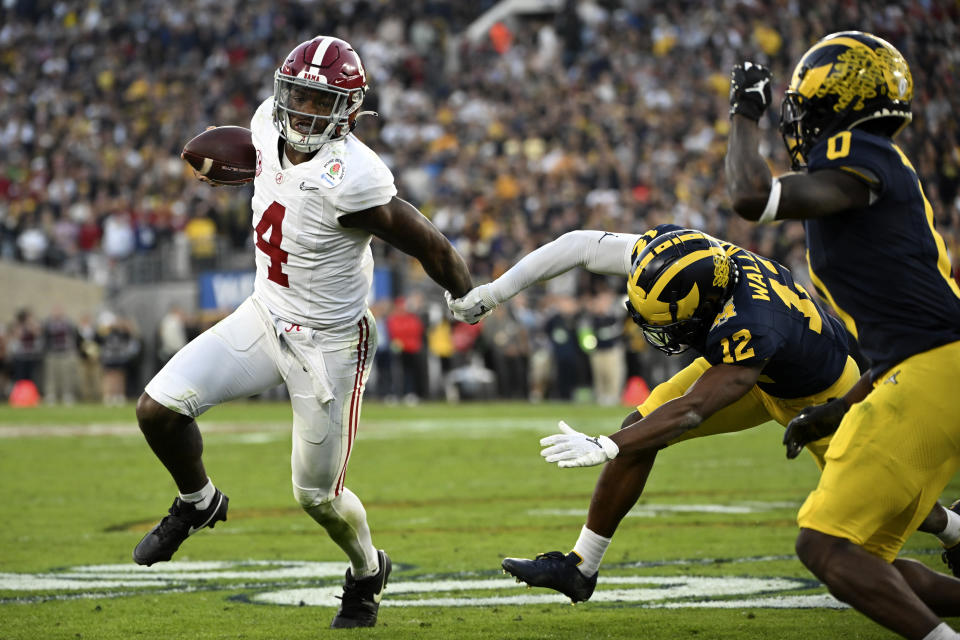 Alabama quarterback Jalen Milroe (4) is chased by Michigan defensive back Josh Wallace (12) during the second half of the Rose Bowl CFP NCAA semifinal college football game Monday, Jan. 1, 2024, in Pasadena, Calif. (AP Photo/Kyusung Gong)