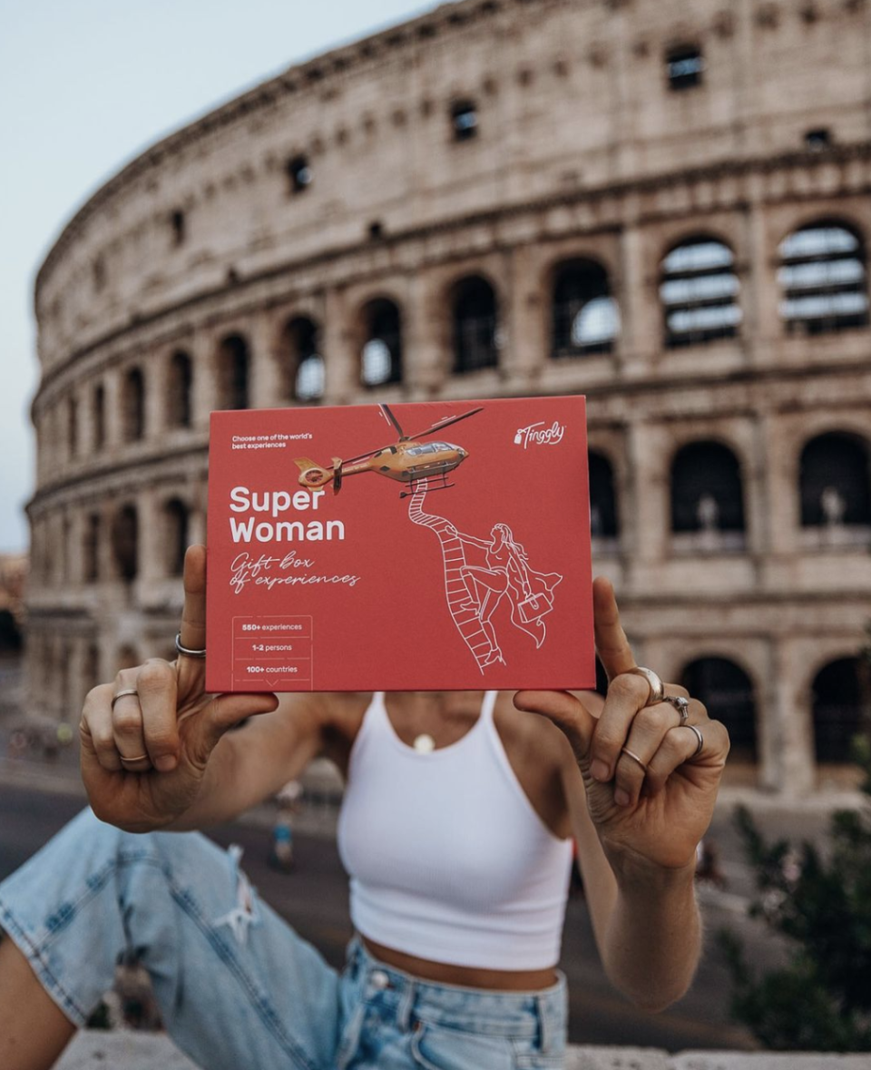 Tinggly Experience Gifts, woman holding red box in front of roman colosseum (Photo via @tinggly/Instagram)