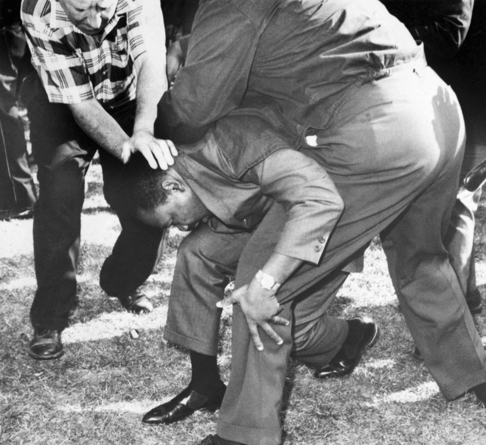 Struck on the head by a rock thrown by a group of hecklers in Chicago, Dr. Martin Luther King falls to one knee. Aug. 5, 1966.