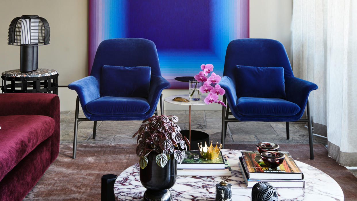  A living room with blue chairs and ombre wall art. 