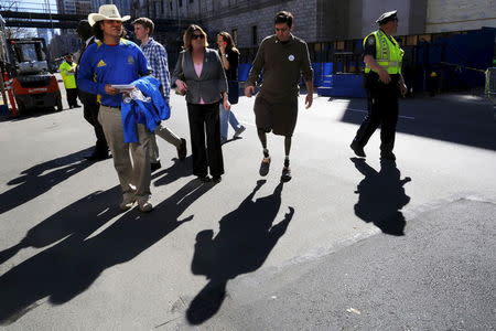 Boston Marathon bombing survivor Jeff Bauman (2nd R) and Carlos Arredondo (L), who helped save Bauman, wait for their car following ceremonies at the site of the first bomb blast on the second anniversary of the bombings in Boston, Massachusetts April 15, 2015. REUTERS/Brian Snyder