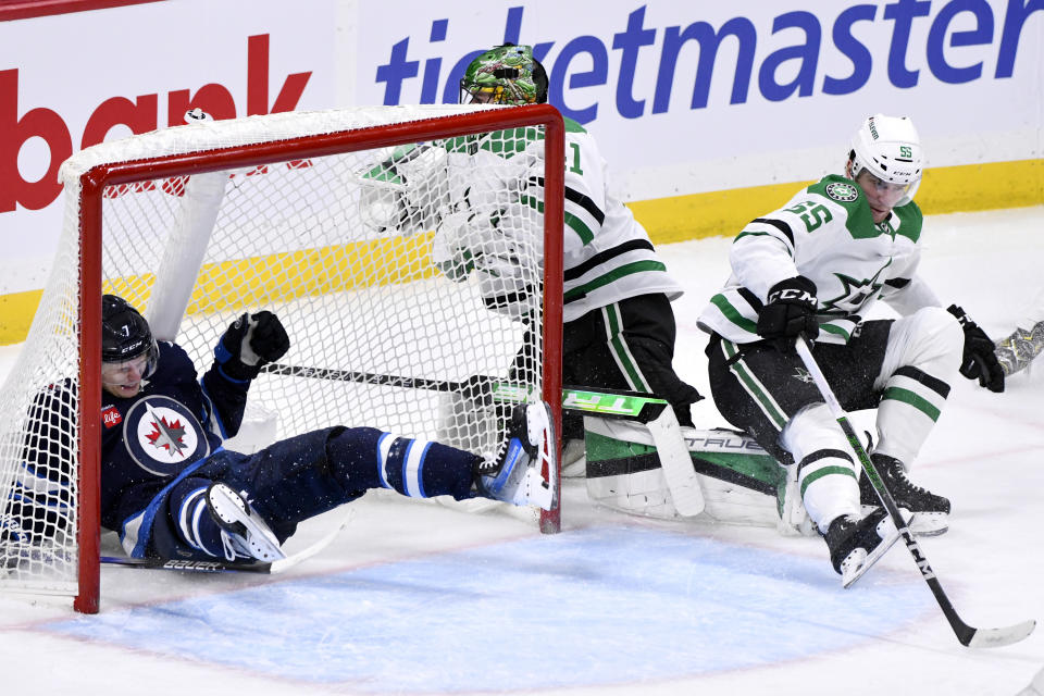 Winnipeg Jets' Vladislav Namestnikov, left, crashes into the net past Dallas Stars' goaltender Scott Wedgewood (41) and Thomas Harley (55) during the third period of an NHL hockey match in Winnipeg, Manitoba, on Saturday, Nov. 11, 2023. (Fred Greenslade/The Canadian Press via AP)