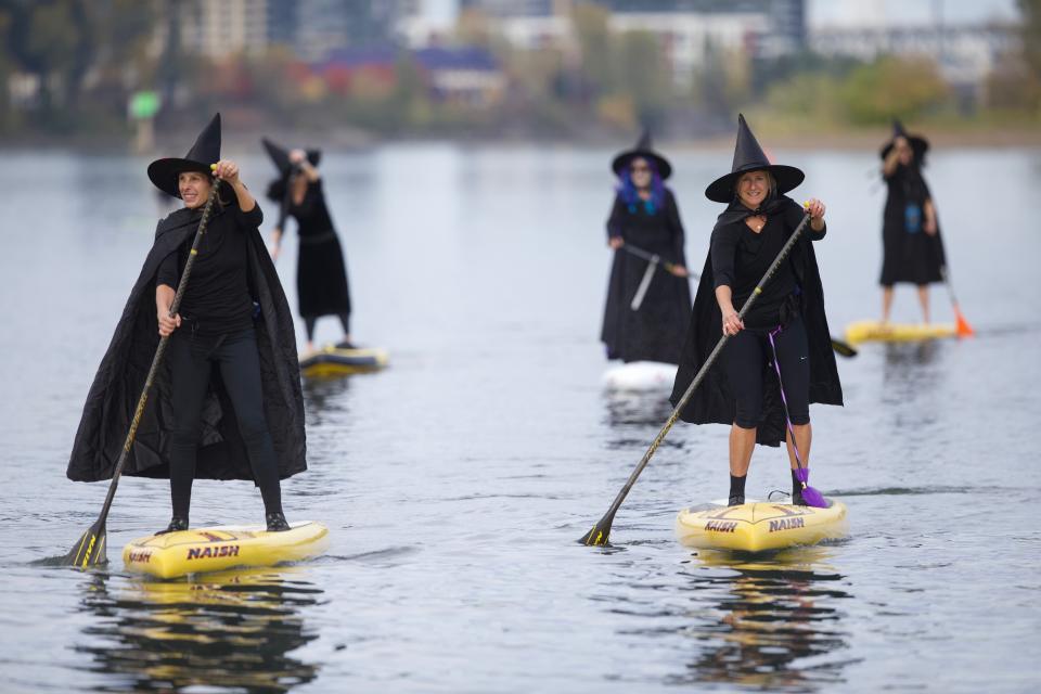 Hundreds of witches, along with a handful of warlocks and wizards, tossed their broomsticks, grabbed paddles and traveled six miles along the Willamette River Saturday, Oct. 27, 2018. The event, called Standup Paddleboard Witch Paddle, dodged days of rain catching a short window of sunshine for the entire three-hour event. The costumed coven cruised for six miles along the Willamette River, which divides the city of Portland. (Mark Graves/The Oregonian via AP)