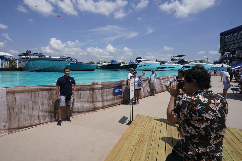 Race fans pose for photos at the man-made marina and beach club during the Formula One Miami Grand Prix auto race at Miami International Autodrome, Friday, May 6, 2022, in Miami Gardens, Fla. (AP Photo/Darron Cummings)