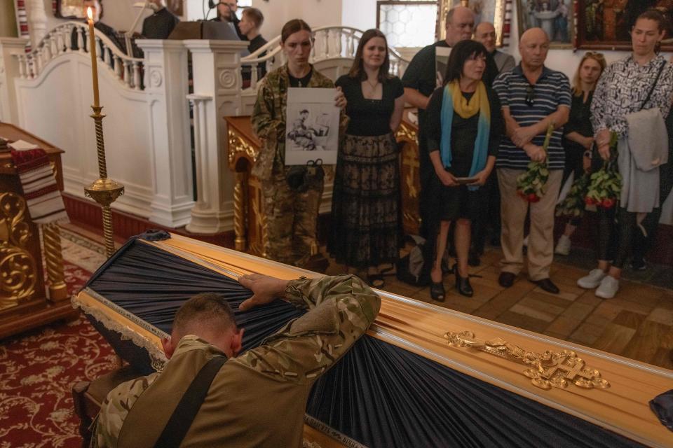 A Ukrainian soldier mourns over the coffin of the violinist and Ukrainian serviceman Davyd Yakushyn, who was killed fighting Russian troops in the Donetsk region (AFP via Getty Images)