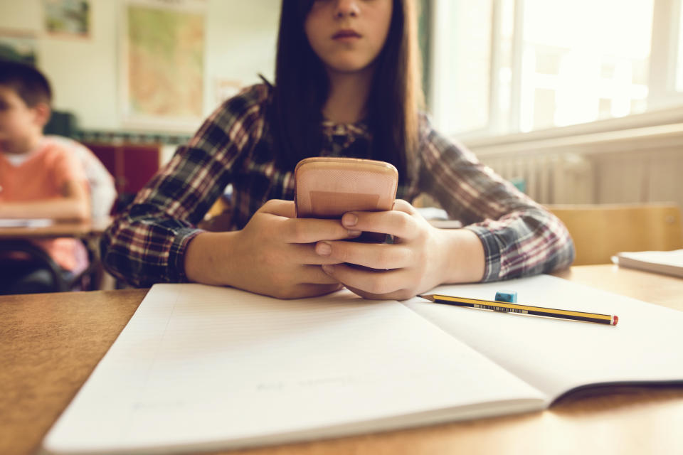 Australian students will no longer be permitted to use their phone in the classroom. Pictured is a stock image of a child using a phone at a desk.