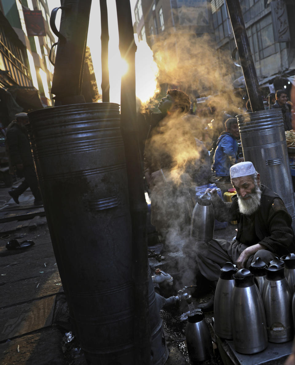 Afghan tea seller Farooq Shah, center, fills kettles with tea for customers at a market place in Kabul, Afghanistan, Wednesday, Dec. 4, 2019. (AP Photo/Altaf Qadri)