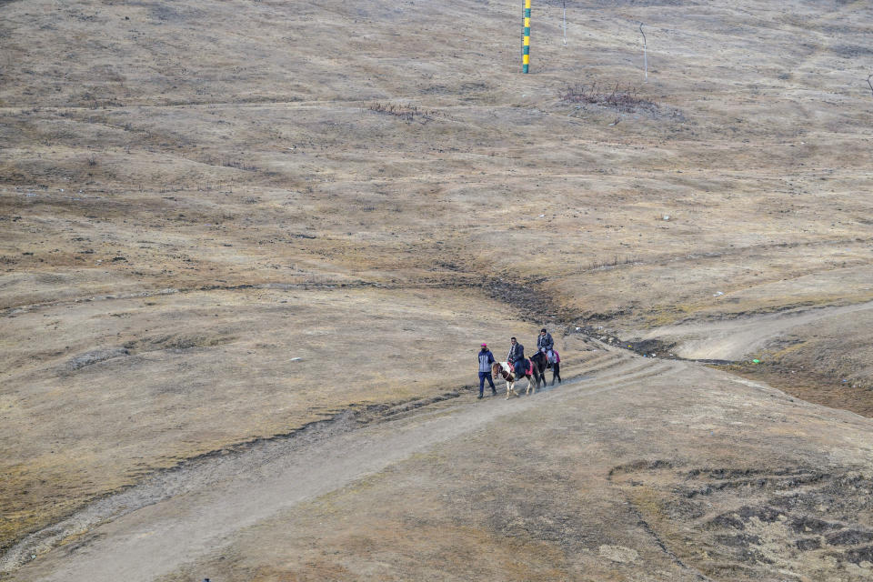 FILE - Tourists ride on horses on a grassy, snowless slope in Gulmarg, northwest of Srinagar, Indian controlled Kashmir, Jan. 25, 2024. For the eighth straight month, Earth was record hot, according to the European climate agency’s analysis of January 2024. (AP Photo/Mukhtar Khan, File)