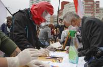 People, wearing face masks to protect against coronavirus, sign to support potential presidential candidates in the upcoming presidential elections in Minsk, Belarus, Sunday, June 14, 2020. The presidential campaign is underway in Belarus despite the coronavirus outbreak after the parliament and government refused to postpone the election scheduled for August 9. (AP Photo/Sergei Grits)