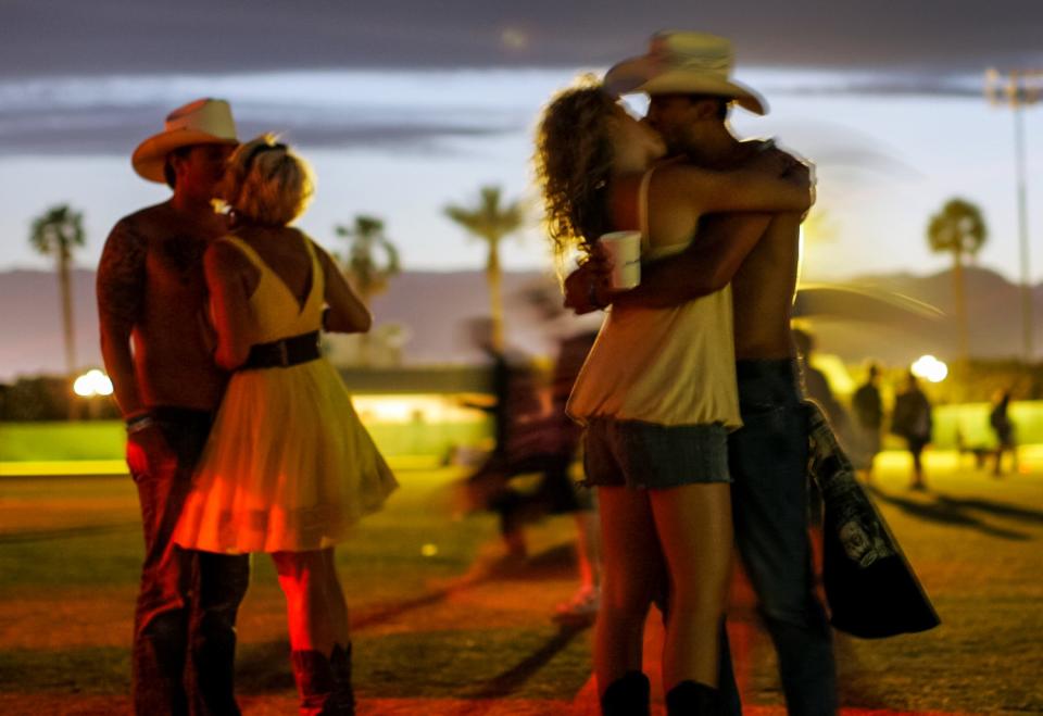 Two couples dancing outdoors stop to kiss