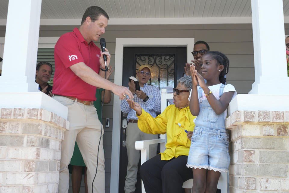 Nelson Mitchell, left, presents Opal Lee, center, with keys for her new home in Fort Worth, Texas, Friday, June 14, 2024. Habitat for Humanity built Lee the home on the same lot where as a child a white mob destroyed her family's home driving them away. (AP Photo/LM Otero)