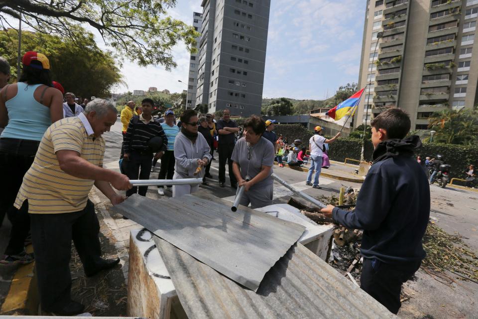 Manifestantes golpean chapas en el barrio de La Boyera en Caracas, Venezuela, el jueves 20 de febrero de 2014. Las protestas han recrudecido en Venezuela mientras el líder opositor Leopoldo López enfrenta cargos criminales por los incidentes ocurridos tras una marcha en Caracas la semana pasada. (AP foto/Fernando Llano)