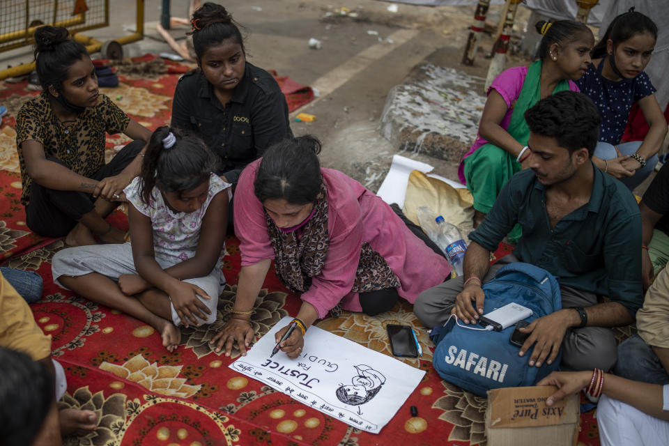 Tina Verma, 27, a social activist, makes a placard at a demonstration site outside a crematorium where a 9-year-old girl from the lowest rung of India's caste system was, according to her parents and protesters, raped and killed earlier this week, in New Delhi, India, Thursday, Aug. 5, 2021. (AP Photo/Altaf Qadri)