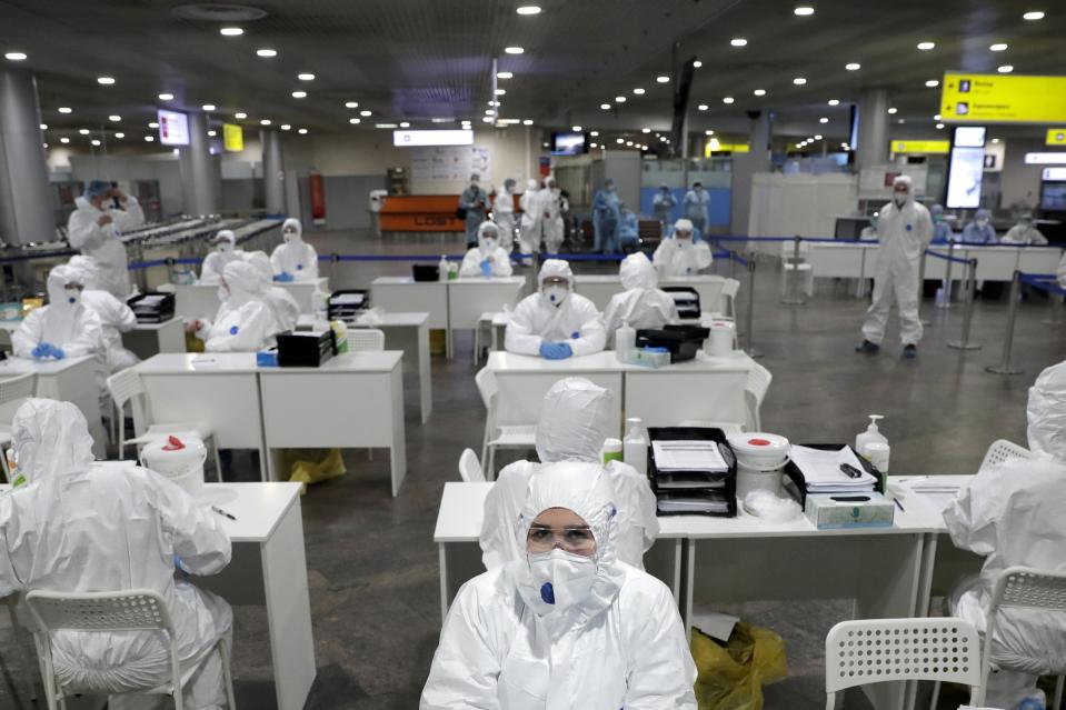 Russian medical experts wait to check passengers arriving from foreign countries at Sheremetyevo airport outside Moscow, Russia, Thursday, March 19, 2020. Authorities in Russia are taking vast measures to prevent the spread of the disease in the country. The measures include closing the border for all foreigners, shutting down schools for three weeks, sweeping testing and urging people to stay home. For most people, the new coronavirus causes only mild or moderate symptoms. For some it can cause more severe illness. (AP Photo/Pavel Golovkin)