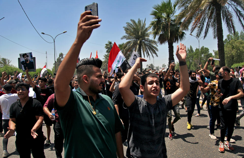 Anti-government protesters chant slogans as they hold posters of slain activists outside the Green Zone area which houses the seat of the country's government and foreign embassies, in Baghdad, Iraq, Tuesday, May 25, 2021. Hundreds of Iraqi protesters have taken to the streets of Baghdad to decry a recent spike in assassinations targeting outspoken activists and journalists. (AP Photo/Khalid Mohammed)