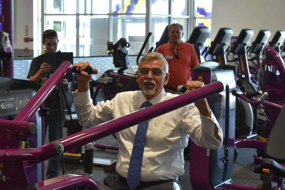 Martinsville mayor Kenny Costin experiments with work out equipment during the grand opening of Martinsville's Planet Fitness on July 29, 2022.