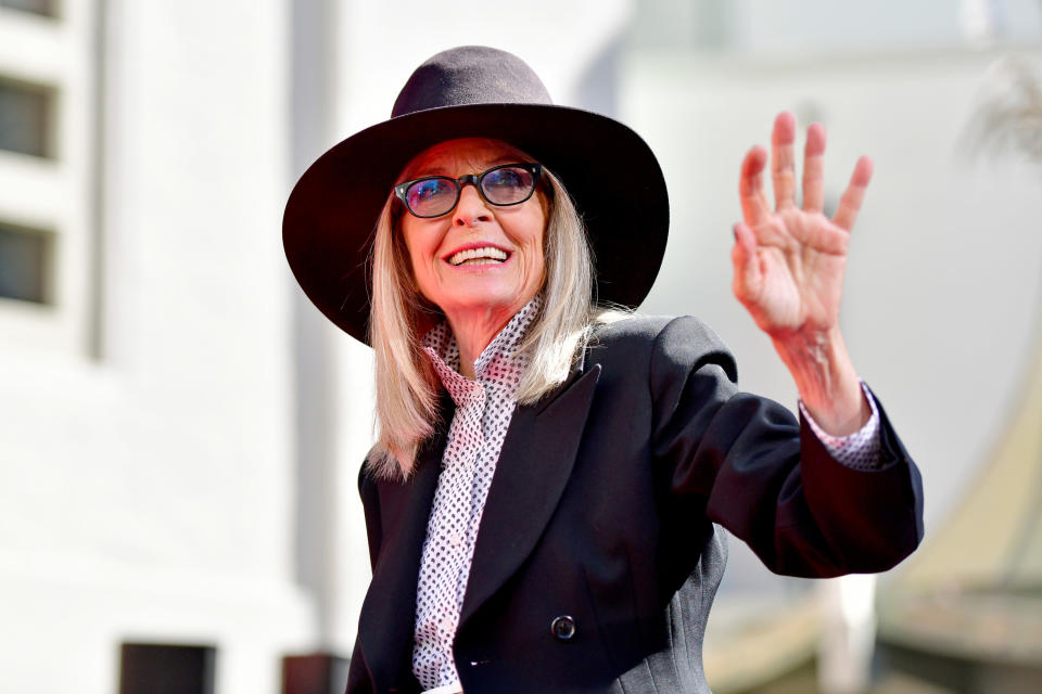Diane wearing a wide-brimmed hat and waving and smiling