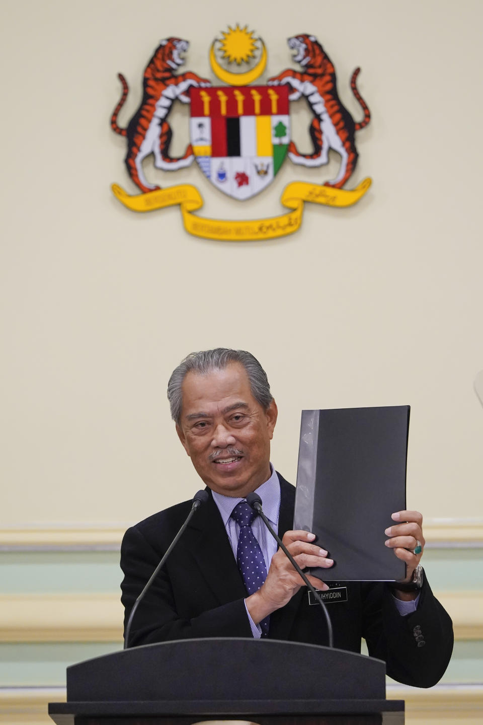 Malaysian Prime Minister Muhyiddin Yassin shows a list of his cabinet ministers during a press conference at his office in Putrajaya, Malaysia, Monday, on March 9, 2020. A key ally has reaffirmed support for Malaysian Prime Minister Muhyiddin Yassin's government, offering him a respite after his failed bid to declare a coronavirus emergency, but his political survival still hangs in the balance. (AP Photo/Vincent Thian)