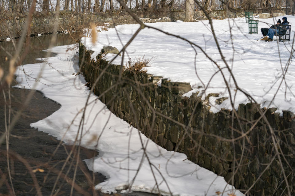 Residents sit on a park bench near the Fall Kill Creek at the Malcolm X Park in Poughkeepsie, N.Y., Tuesday, Jan. 25, 2022. Poughkeepsie was rated by the New York comptroller as the state’s most financially stressed community in 2020. The more than $20 million it is getting from the American Rescue Plan cannot be used to wipe out the deficit, but the city plans to make major improvements to parks and swimming pools, including a complete rebuild of a run-down bathhouse that has been relying on portable toilets. (AP Photo/Mary Altaffer)