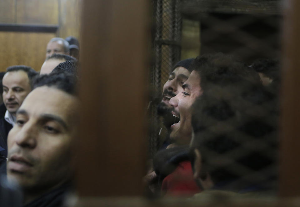 FILE - Police officers surround the cell in a courtroom as some of 26 men, who were arrested in a televised raid last month by police looking for gays at a Cairo public bathhouse, celebrate after an Egyptian court acquitted them in Cairo, Egypt, Monday, Jan. 12, 2015. The trial, which had caused an uproar among activists and rights groups, captured public attention after a pro-government TV network aired scenes of half-naked men being pulled from the bathhouse by police. (AP Photo/Amr Nabil, File)