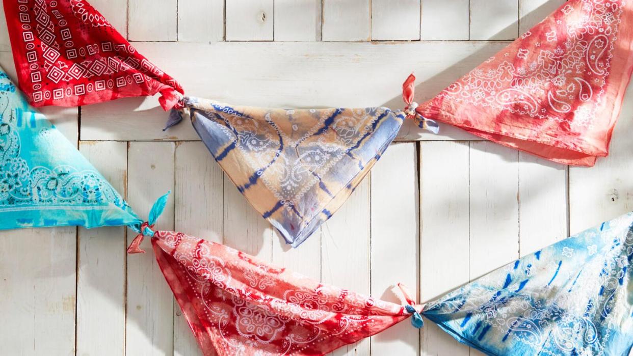tie dyed bandanas tied into a bunting hung on a white wall