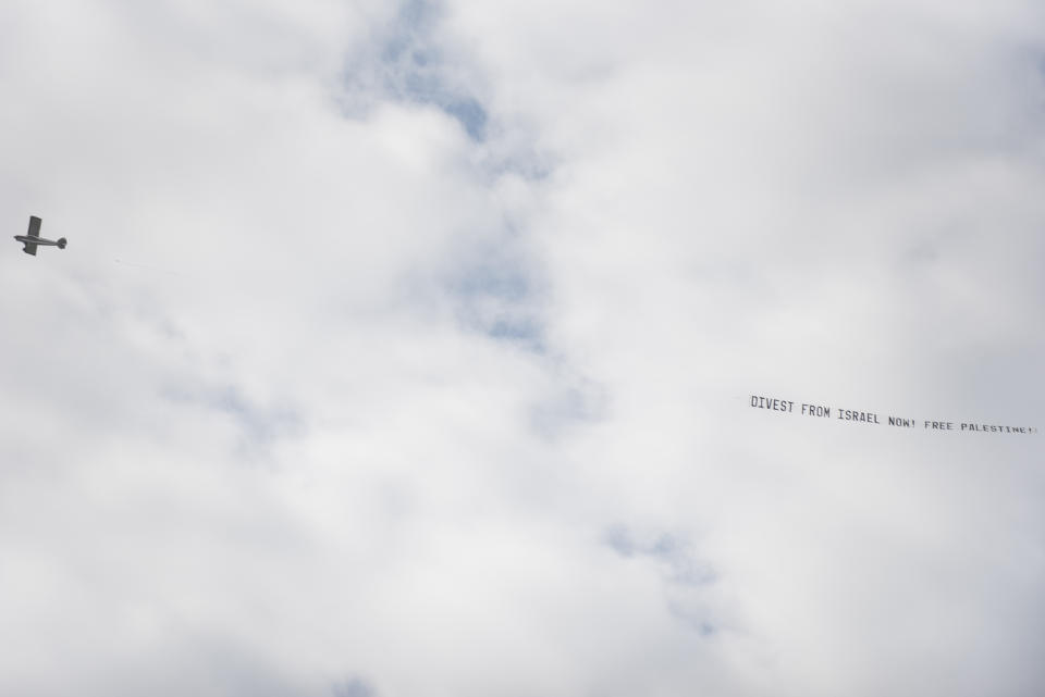 CORRECTS PHRASE ON BANNER - A plane pulling a banner that reads "Divest From Israel Now! Free Palestine" flies overhead before the University of Michigan's Spring 2024 Commencement Ceremony at Michigan Stadium in Ann Arbor, Mich., on Saturday, May 4, 2024. (Katy Kildee/Detroit News via AP)
