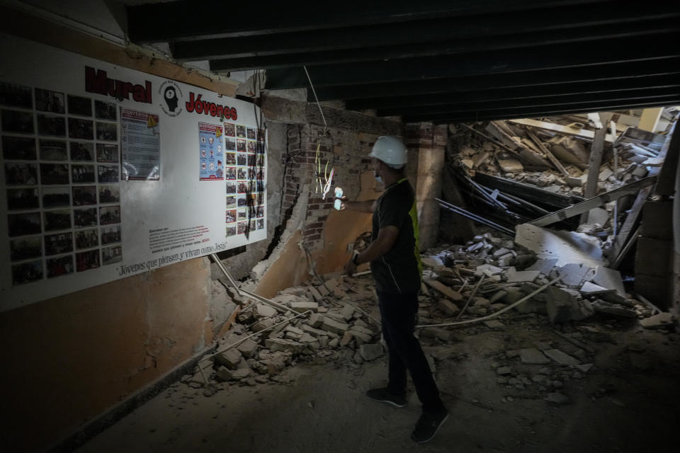 Rev. David Gonzalez uses his phone to illuminate damage inside the Calvary Baptist Church, caused by an explosion that devastated the nearby Hotel Saratoga, in Old Havana, Cuba, Wednesday, May 11, 2022. “For each believer, each Christian, each Baptist who comes, this is their home,” said Gonzalez, 31, who has lived for the past two years in an apartment beside the church that is now partially collapsed. (AP Photo/Ramon Espinosa)