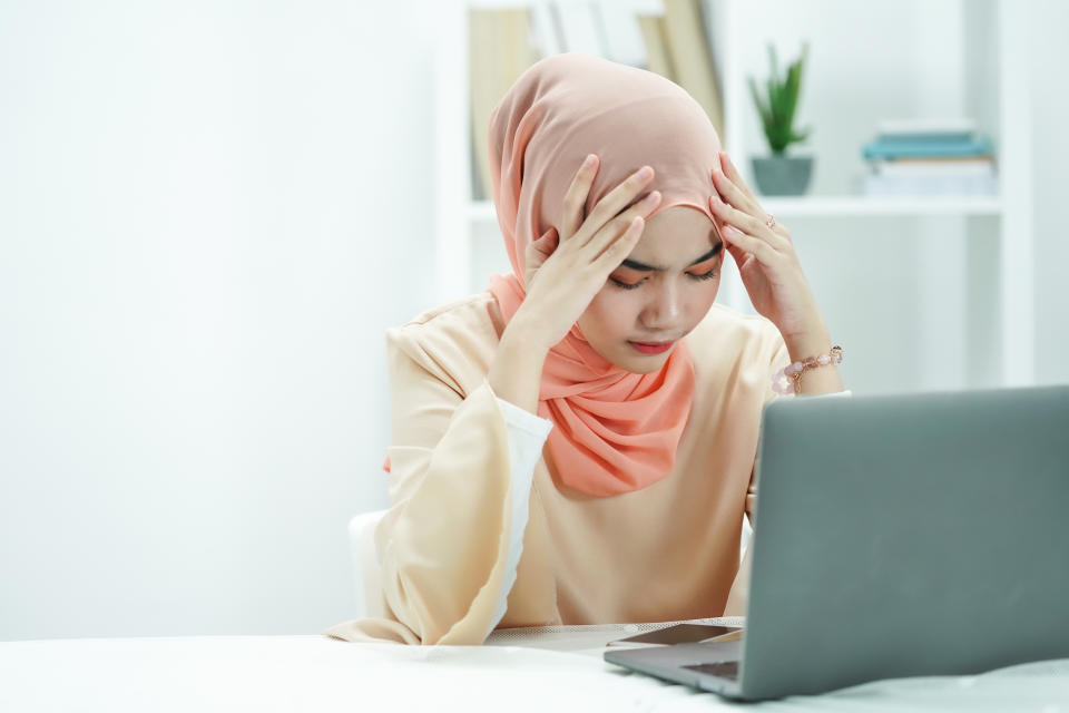 Stressed Muslim businesswoman feeling sick and tired while working a in office. girl is feeling headache when working.