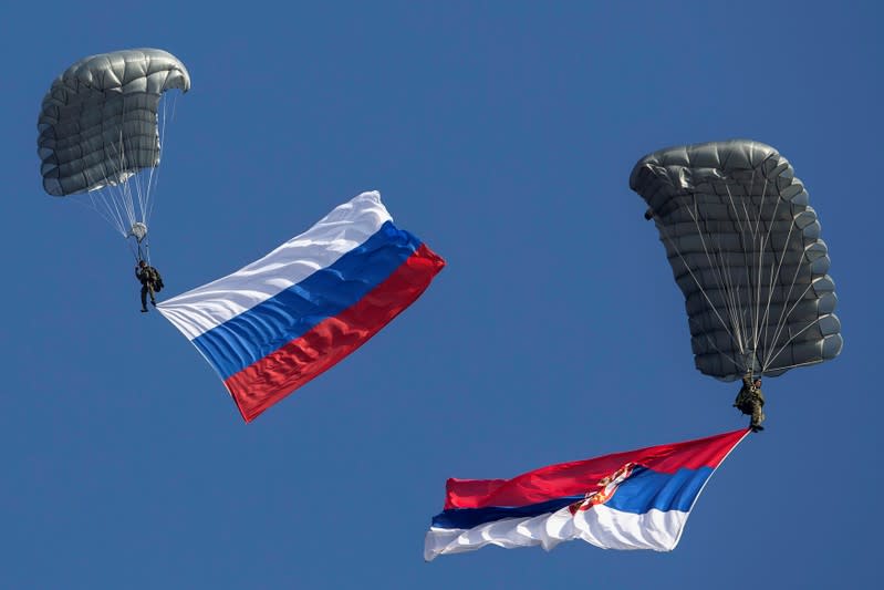 FILE PHOTO: Serbian paratroopers descend to the ground holding Serbian and Russian national flags during a training exercise in the village of Nikinci