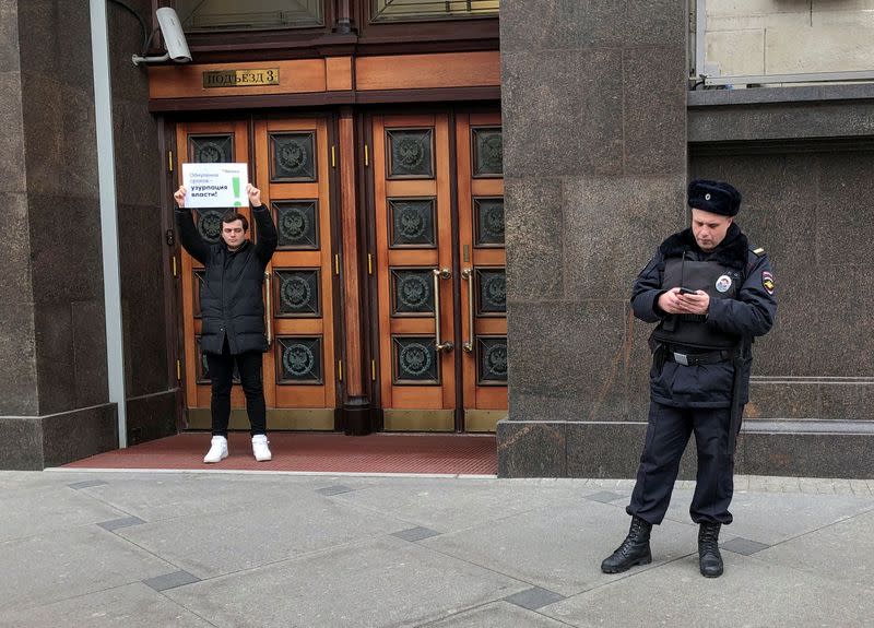 A participant of a single-person protest holds a placard during a session of Russia's lower house of parliament to consider constitutional changes in Moscow