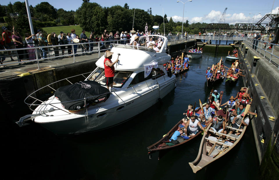 FILE - This July 31, 2006 file photo shows boats and tribal canoes taking part in the taking part in a Tribal Journey in the Ballard Locks in Seattle. The Tribal Journey is held every year as a way to preserve Indian heritage and promote positive lifestyles for Indian youth. Known locally as the Ballard Locks, this water gateway constructed and run by the U.S. Army Corps of Engineers separates the salty Puget Sound from Lake Union and Lake Washington using a system of water elevators. Recreational, tourist, working and research vessels make their way through the locks every day, lowering and elevating before crowds of onlookers. It's an engineering gem that opened in 1917, a miniature Panama Canal in the middle of the city. (AP Photo/Ted S. Warren, file)