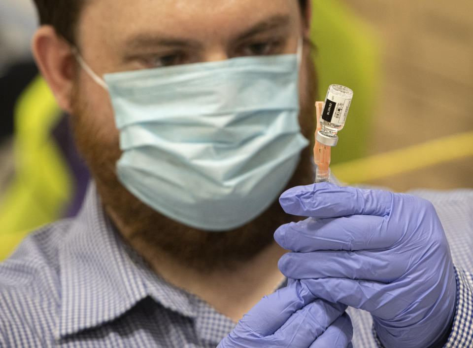 North East Ohio Medical University student William Puthoff prepares a dose of Johnson & Johnson COVID-19 vaccine at Kent State University in Kent, Ohio, Thursday, April 8, 2021. U.S. colleges hoping for a return to normalcy next fall are weighing how far they should go in urging students to get the COVID-19 vaccine, including whether they should — or legally can — require it. (AP Photo/Phil Long)