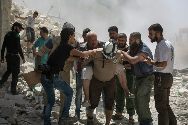 Syrians carry a wounded man following a reported barrel bomb attack by government forces in the opposition-held district of Al-Mashhad near Aleppo on July 26, 2016