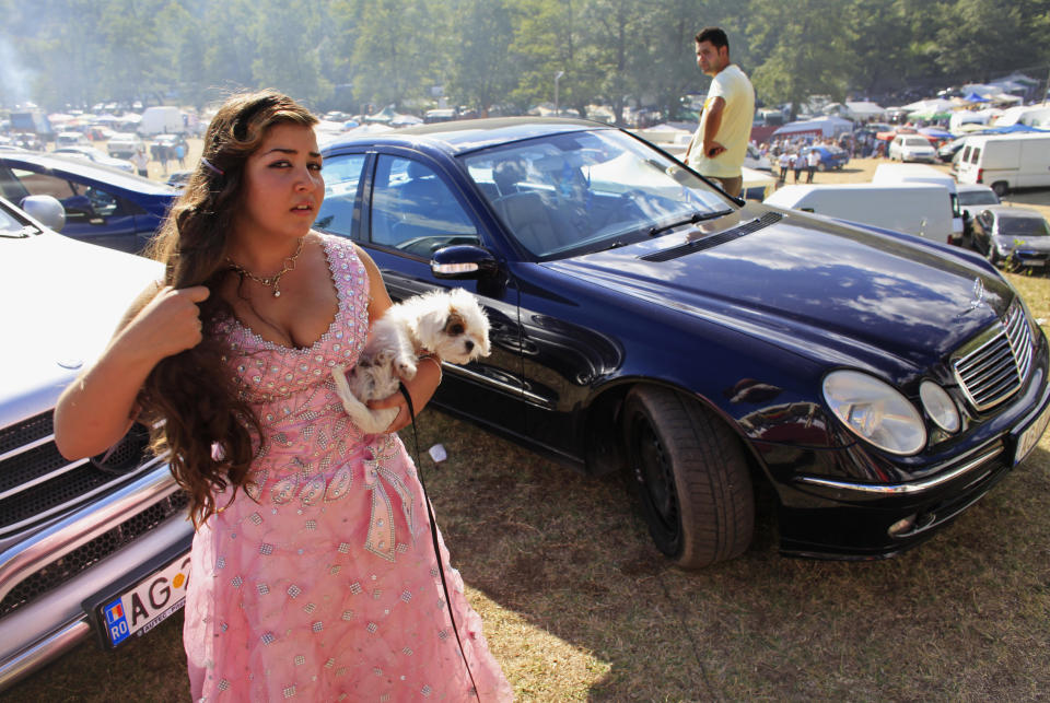 A Roma girl holds her pet dog during the traditional ethnic Roma festival in Costesti, 210 km (128 miles) west of Bucharest, September 8, 2012. Following their tradition, thousands of Roma from all over Romania, which has Europe's largest Roma community, gather every year to celebrate the birthday of St. Mary, to make wedding arrangements for their sons and daughters and to show off their wealth. REUTERS/Radu Sigheti (ROMANIA - Tags: SOCIETY RELIGION ANIMALS)