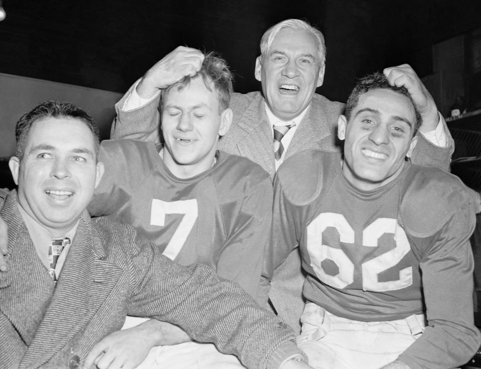 In this Dec. 28, 1947 file photo, Chicago Cardinals coach Jimmy Conzelman musses the hair of running backs Charley Trippi, right, and Elmer Angsman as assistant coach Phil Handler, left, grins in the dressing room in Chicago after the the Cardinals beat the Philadelphia Eagles 28-21 in the NFL championship game.
