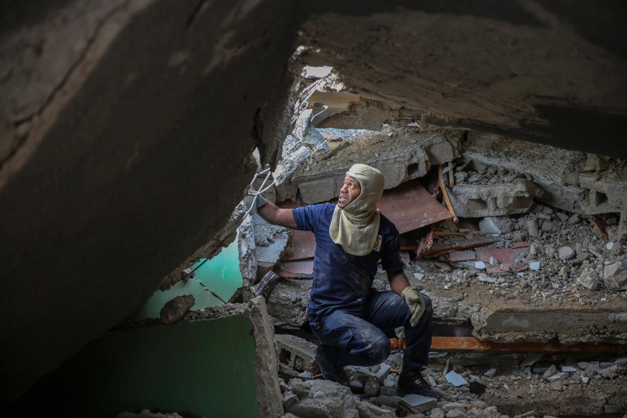 A firefighter searches for survivors inside a damaged building, after Saturday's  7.2 magnitude earthquake in Les Cayes, Haiti, Sunday, Aug. 15, 2021.